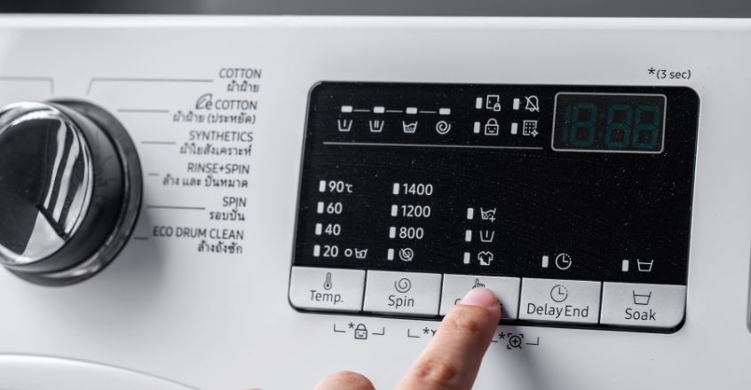 Mano ajustando configuración de lavadora eficiente para reducir consumo de electricidad