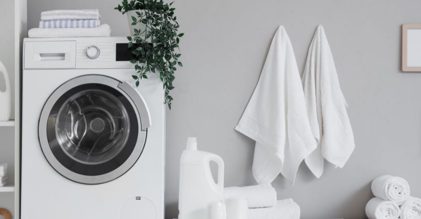 Lavadora con toallas y detergente en lavandería moderna, ejemplo práctico para reducir consumo de electricidad.