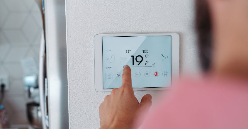Persona ajustando termostato digital en casa para optimizar la temperatura y reducir consumo de electricidad
